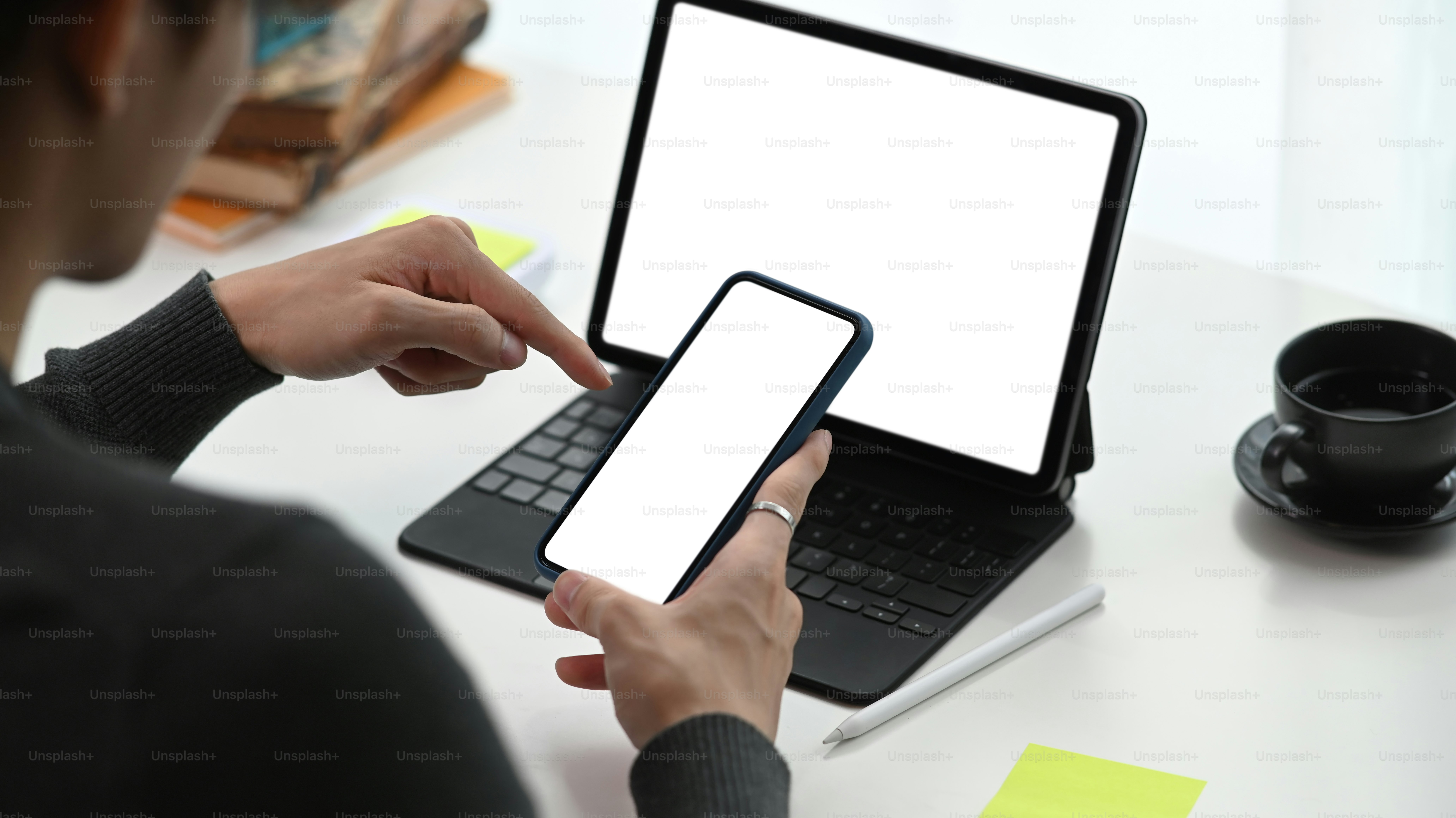 Cropped shot of young man working with computer tablet and using mobile phone.